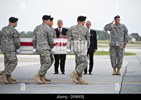 US-Verteidigungsminister Chuck Hagel, links, steht seine Hand über sein Herz mit Secretary Of The Army John McHugh und Army Chief General Ray Odierno als weiß behandschuhten Soldaten die Fahne drapiert Fall tragen die Reste der Armee Pfc. Cody aus einer c-17 Frachtflugzeug auf der Dover Air Force Base in Dover, DE 9. Oktober 2013 durchgeführt.  Hagel hat angekündigt, dass das Hausfundament Fisher die Familien der gefallenen Soldaten Tod Vorteile bieten wird, die vom Pentagon durch die Regierung Herunterfahren bezahlt werden können. Stockfoto