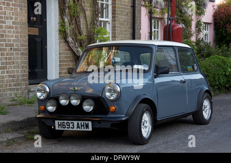 Oldtimer. Ein Austin Mini geparkt in der High Street von der malerischen Dorset Dorf Sydling St. Nikolaus. Dahinter befindet sich ein Vintage Zapfsäule. England. Stockfoto