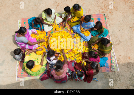 Ländliche Indianerdorf Frauen und Kinder sitzen rund um einen Korb mit Ringelblumen machen Blumengirlanden. Andhra Pradesh, Indien Stockfoto