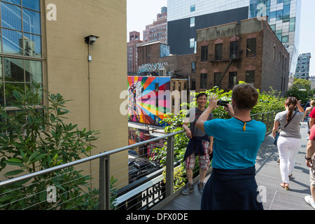 Eine Frau, die ein Foto von seinen Freund / Ehemann mit einem Handy im Highline Park in New York City Stockfoto