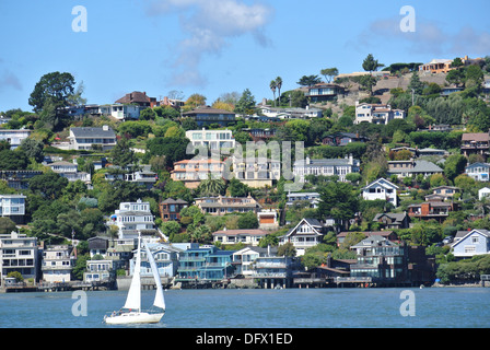 Segelboot segeln vorbei an Wasser und Häuser auf Hügeln in Tiburon, Kalifornien Stockfoto