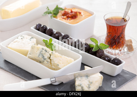 Vorspeisen-Blauschimmelkäse und schwarz marinierte Oliven auf dem Schiefer Käse Schneidebrett mit türkischem Stil heißen Tee und Hummus Stockfoto