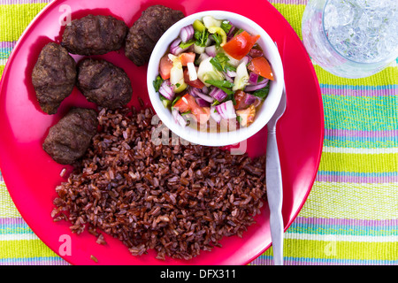 Türkische Fleisch Kugeln Köfte serviert mit roten Reis Pilaf und türkischen Shepperd Salat auf einer roten Platte zusammen mit Eiswasser. Stockfoto