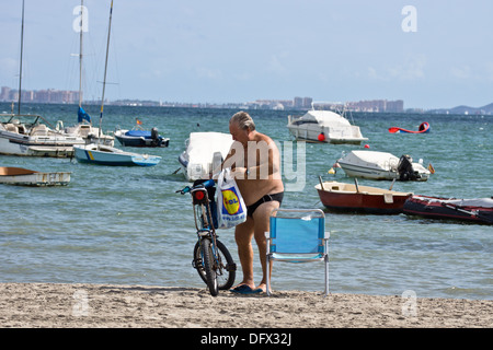 Ein Mann am Strand mit ein hochklappen Stuhl und Push Bike und seine Lidl-Tasche Stockfoto