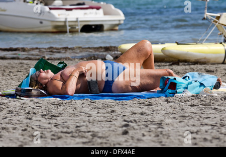 Übergewichtige Frau, Sonnenbaden am Strand in Spanien Stockfoto