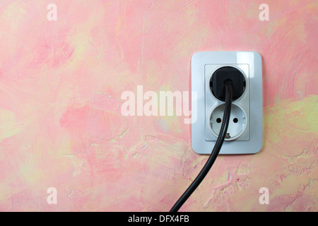 Weiße Buchse und Kabel an Rosa Wand. Doppelsteckdose Stockfoto