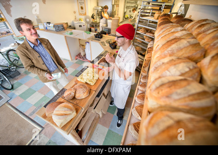 Funktion auf dem Bristol-Pfund - The East Bristol Bakery, Inhaber und Leiter Baker Alex Poulter dient ein Kunde Aug 2013 Stockfoto