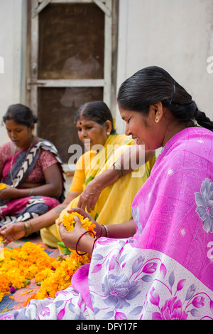 Ländliche Indianerdorf Frauen sitzen rund um einen Korb mit Ringelblumen machen Blumengirlanden. Andhra Pradesh, Indien Stockfoto