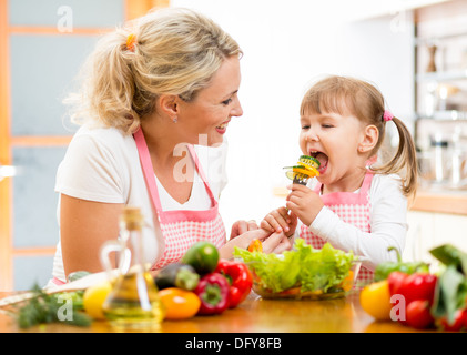 Mutter füttert Kind Tochter Gemüse in der Küche Stockfoto