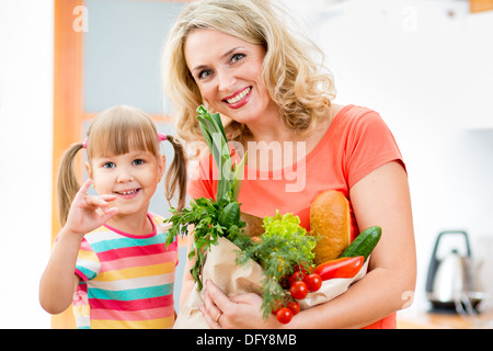 Mutter und Kind hält eine Einkaufstüte voll mit Gemüse in der Küche Stockfoto