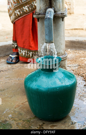 Ländliche Indianerin Kunststoff Wassertopf aus einem ländlichen Wasser-Pumpe zu füllen. Andhra Pradesh, Indien Stockfoto