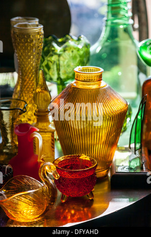 Farbige Ornamentgläser Vasen, Gläser und dekorative Figuren auf einem Tisch angeordnet. Stockfoto