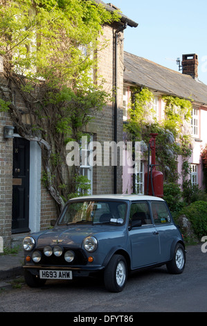 Oldtimer. Ein Austin Mini geparkt in der High Street von der malerischen Dorset Dorf Sydling St. Nikolaus. Dahinter befindet sich ein Vintage Zapfsäule. England. Stockfoto