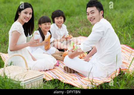 Glückliche junge Familie mit einem Picknick auf dem Rasen Stockfoto