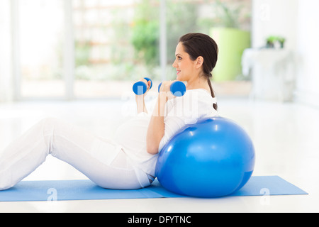 ziemlich schwangere Frau das Training mit Hanteln zu Hause Stockfoto