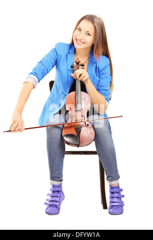 Lächelnde junge Frau sitzt auf einem Holzstuhl, Geige zu spielen Stockfoto