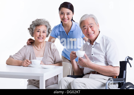 Senioren mit einem Kaffee Pause mit Pflegehelferin Stockfoto