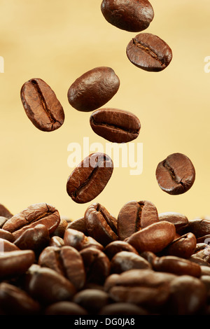 Kaffeebohnen fallen auf Haufen vor braunem Hintergrund Stockfoto