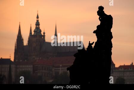 Blick auf den Stein Skulptur der Madonna mit St.Dominic und Thomas Aquinas vor der Silhouette der Prager Burg und St. Vitus Cathedral auf der Karlsbrücke in Prag, Tschechische Republik, bei Sonnenuntergang am 8. Oktober 2013. Foto: Sebastian Kahnert Stockfoto