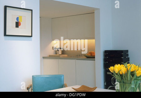 Bild über dem Tisch mit türkisfarbenen Stuhl und Vase mit gelben Tulpen im Essbereich Küche in moderner Wohnung Stockfoto