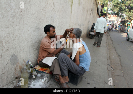 Straße Barbier rasieren einen Mann mit einer offenen Rasierklinge auf einer Straße in Kolkata, Westbengalen, Indien am 26. November 2012 Stockfoto