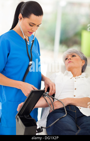 wunderschöne Arzt senior Patient Blutdruck überprüfen Stockfoto