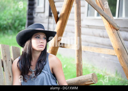 junge Cowgirl in Stetson auf Holz Gartenschaukel Stockfoto