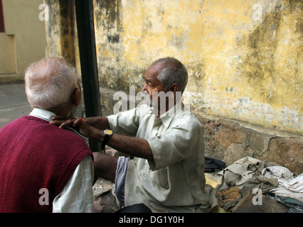 Straße Barbier rasieren einen Mann mit einer offenen Rasierklinge auf einer Straße in Kolkata, Westbengalen, Indien am 30. November 2012 Stockfoto