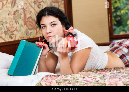 Hübsche Frau halten angebissene Apfel und Blick fraglich Stockfoto