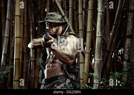Soldat mit Messer und Gewehr im Bambuswald Stockfoto