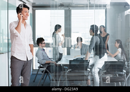 Junger Mann am Telefon außerhalb Vorstandsetage Stockfoto
