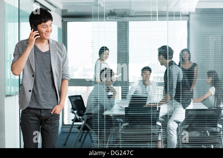 Junger Mann am Telefon außerhalb Vorstandsetage Stockfoto