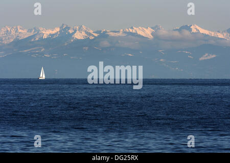 Meersburg, Deutschland. 11. Oktober 2013. Ein Schiff fährt auf dem Bodensee vor der Schweizer Alpen kurz vor Sonnenuntergang in Meersburg, Deutschland, 11. Oktober 2013. Foto: Felix Kästle/Dpa/Alamy Live News Stockfoto