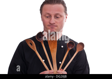 Ein Koch blickt auf fünf Kochlöffel in seinen Händen Stockfoto