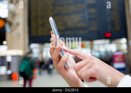 Frau mit ihrem Handy in Halle Bahnhof. Schließen Sie die Hände Stockfoto