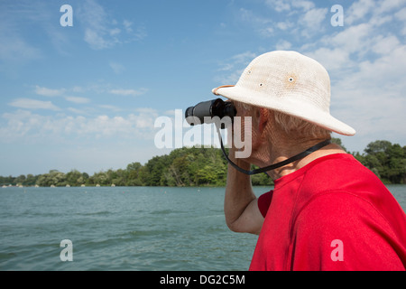 älterer Herr Blick durch ein Fernglas gegen den Himmel Stockfoto