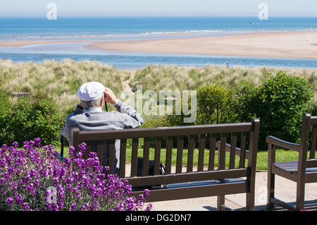 Mann auf der Bank sitzen und Blick auf das Meer Alnmouth Northumberland, England, UK Stockfoto