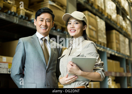 Weibliche Logistikmitarbeiter mit Geschäftsmann im Lager Stockfoto