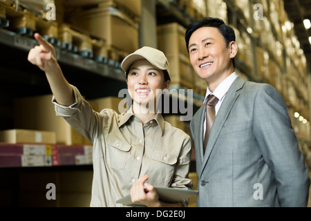 Weibliche Logistikmitarbeiter mit Geschäftsmann im Lager Stockfoto