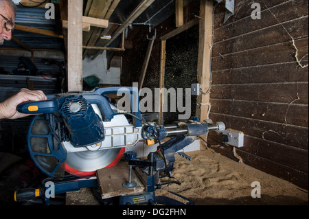 Eine gleitende zusammengesetzte Mitra sah, in einem Workshop schneiden Holz mit Sägemehl, von der Rückseite der Säge ausgeworfen. Stockfoto