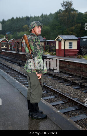 1940 Kriegszeit Armee Mann an Levisham. North Yorkshire, UK. 11. Oktober, 2013. Feldgendarmerie an die "Eisenbahn in Kriegszeiten "North Yorks Moors Railway (NYMR) Fall an Levisham Bahnhof in schlechtem Wetter am Wochenende 12. und 13. Oktober 2013. Levisham, war mit Postern dekoriert, und Französisch während der Kriegszeit (NYMR) 'Wochenende'' Le Visham zu werden' im Norden Frankreichs. Die Sammlung, die Erholung von einem französischen Dorf im Zweiten Weltkrieg besetzten, Zweiter Weltkrieg, Zweiter Weltkrieg, Weltkrieg, WW2 deutscher Truppen. Stockfoto