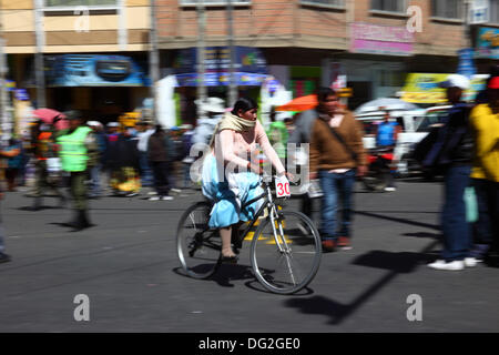 El Alto, Bolivien. Oktober 2013. Ein Teilnehmer reitet an Zuschauern vorbei, während sie an einem Cholitas-Fahrradrennen für indigene Aymara-Frauen teilnimmt. Das Rennen findet auf einer Höhe von etwas mehr als 4.000 m entlang der Hauptstraßen in El Alto (oberhalb von La Paz) zum bolivianischen Frauentag statt, der gestern Freitag, den 11. Oktober war. Quelle: James Brunker / Alamy Live News Stockfoto
