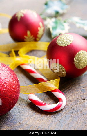 Ein Pfefferminz Bonbon Stöcke mit Weihnachtskugeln und Holly Blätter. Stockfoto