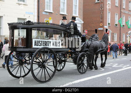 Dublin, Irland. 12. Oktober 2013. Ein Pferd gezogene Leichenwagen führt den Protestmarsch, bedeutet den Tod durch Sparmaßnahmen. Gewerkschaften forderten einen Protestmarsch durch Dublin, vor der Ankündigung des Haushaltsplans 2014 nächste Woche. Sie protestierten gegen Kürzungen bei Bildung, Soziales und Gesundheit und für eine Nutzung alternativer Einnahmequellen durch die Regierung. © Michael Debets/Alamy Live-Nachrichten Stockfoto