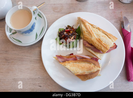 Gute Mittagsimbiss Brie und Speck sandwich in französisches Brot mit gemischtem Salat und eine Tasse Tee Stockfoto