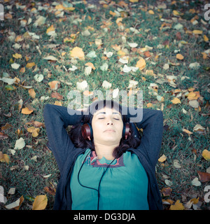 junge schöne Frau anhören von Musik im Park im Herbst Stockfoto