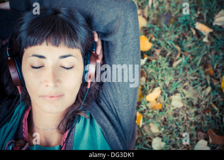 junge schöne Frau anhören von Musik im Park im Herbst Stockfoto