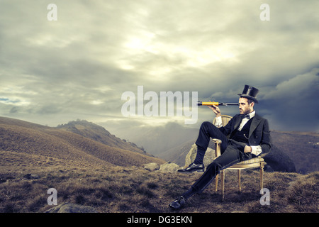 Gentleman mit einem Teleskop auf einem Berge Ödland Stockfoto