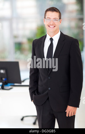 hübscher junger Geschäftsmann, stehend im Büro Stockfoto