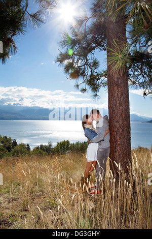 Vertikale Outdoor-Foto der jungen Erwachsenen Paares umfassend in einer Wiese über dem See. Stockfoto